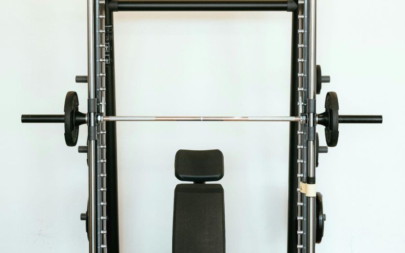 Power racks are a versatile tool for strength training, offering safety and stability for lifting heavy weights. This guide explores key exercises to maximise your power rack workouts. Understanding Power Racks A power rack is a cage-like structure with adjustable uprights and safety features like spotter arms. These features allow you to lift with confidence, pushing yourself to build strength and muscle. Benefits of Power Racks Safety: Safety pins catch the barbell if you fail a rep, minimising injury risk. Stability: The rack provides a stable platform for exercises like squats and bench press. Versatility: Power racks often have pull-up bars, dip bars, and other attachments for various exercises. Top 6 Power Rack Exercises Squats: The king of lower body exercises, squats target quads, hamstrings, glutes, and calves. The power rack allows safe squatting with heavy weights. Enhance your power rack workouts with squat variations: Goblet Squats: Hold a dumbbell or kettlebell in front of your chest to target quads, glutes, and core. Front Squats: Emphasise quads and core by resting the barbell on the front of your shoulders. Bulgarian Split Squats: Target quads, glutes, hamstrings for improved balance and stability. Pistol Squats: Strengthen quads, glutes, core with this balance-demanding variation. Bench Press: A classic upper body exercise, the bench press targets the chest, shoulders, and triceps. The power rack provides stability for lifting heavier weights. The bench press targets chest, shoulders, and triceps. Using a power rack for bench press ensures safety, stability, and allows for lifting heavier weights to build upper body strength. Steps for bench press in a power rack: Set safety pins just below chest level. Position the barbell at arm's length. Lie down so the bar is above your eyes. Lower the bar to your chest. Push back up, fully extending arms. Repeat for desired reps. Maintain proper form and technique to prevent injury and maximize effectiveness while performing the bench press exercise. Pull-Ups/Chin-Ups: These compound exercises target the back, biceps, and shoulders, and improve core stability. The power rack allows for proper form and technique. Pull-ups and chin-ups target the back, biceps, and shoulders, engaging core muscles for strength and stability. Use a power rack for stability and focus on form: Set up the pull-up bar at the right height. Grab the bar with an overhand (pull-ups) or underhand grip (chin-ups). Hang with arms extended and core engaged. Pull up until your chin clears the bar. Slowly lower back down. Repeat for desired reps. Overhead Press: This exercise strengthens shoulders and triceps. The power rack allows for a greater range of motion and provides safety. The overhead press, or military press, targets shoulder and tricep muscles. It's key for upper body strength and stability. Using a power rack enhances range of motion and safety. To do the overhead press in a power rack: Set safety pins just below shoulder level. Place the barbell at shoulder height. Stand in front of the bar, grip it slightly wider than your shoulders. Lift the bar overhead, arms fully extended. Lower the bar to shoulder level, elbows slightly bent. Repeat for desired reps. Incorporating this exercise boosts shoulder strength and overall upper body power. 5. Barbell Rows: Barbell rows target the back muscles, promoting overall development. The power rack allows for safe and controlled execution. Barbell rows target back muscles for complete development, engaging lats, rhomboids, traps, biceps, forearms, and core. Set up the bar in a power rack at the right height. Stand with feet shoulder-width apart, hinge at the hips to grab the bar with an overhand grip, and maintain a neutral spine. Pull the bar towards your lower chest while keeping your back straight and squeezing your shoulder blades together. Lower the bar in a controlled manner and repeat. Focus on maintaining proper form and gradually increase weight as you get stronger. 6. Deadlifts: Deadlifts are a full-body exercise that tests overall strength. The power rack allows for a safe setup and easy loading/unloading of weights. For safe deadlifts on a power rack: Adjust J-hooks or uprights to mid-shin level. Place the barbell aligned with J-hooks. Approach bar with shoulder-width stance, flat back. Grasp bar just outside shoulder-width. Push through heels to lift the bar, maintaining form. Lower bar in controlled manner, touch floor between reps. Advanced Power Rack Exercises: Once you've mastered the foundational exercises, the power rack opens doors to more targeted movements for sculpted physiques and increased strength. Pin Squats: Set the safety pins just below your sticking point in a squat. This eliminates momentum and forces you to build power through the entire movement, strengthening specific weaknesses. Safety Squat Variations: Utilise the safety pins for front squats, overhead squats, or Bulgarian split squats. These variations target different muscle groups while maintaining safety with heavy weights. Incline/Decline Bench Press: Adjust the rack benches for incline or decline variations of the bench press. This emphasises the upper or lower pec muscles, respectively, for a more complete chest workout. Landmine Exercises: Attach a barbell landmine attachment to the rack. This allows for unique exercises like single-arm rows, shoulder presses, and rotational movements that challenge core stability and improve overall athleticism. Power Rack Training Tips: Warm-up: Before lifting heavy weights, perform dynamic stretches and light weight exercises to prepare your muscles and joints. Progression: Gradually increase weight, sets, and reps as you get stronger. Don't sacrifice form for heavier weights. Mind-Muscle Connection: Focus on the targeted muscle group during each exercise for optimal results. Rest Periods: Allow sufficient rest (usually 1-3 minutes for compound lifts) between sets to recover and maintain proper form. Form Check: Use a mirror or video recordings to ensure proper form and avoid injuries. By incorporating these exercises, advanced variations, and training tips, you can transform your power rack workouts into a well-rounded program for building strength, muscle mass, and overall fitness. Remember, consistency and proper technique are key to unlocking the full potential of power rack training. Conclusion Power rack exercises can significantly enhance your strength training. Master the proper techniques for these exercises to maximise your workouts and achieve your fitness goals. Remember to focus on form and control to get the most out of your power rack training.